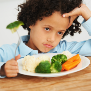 Kid frowning at plate of vegetables