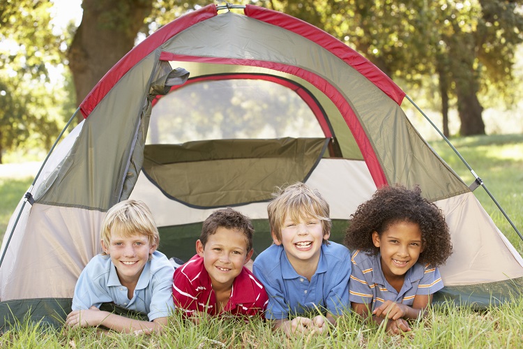 Group of children camping with tent over grass